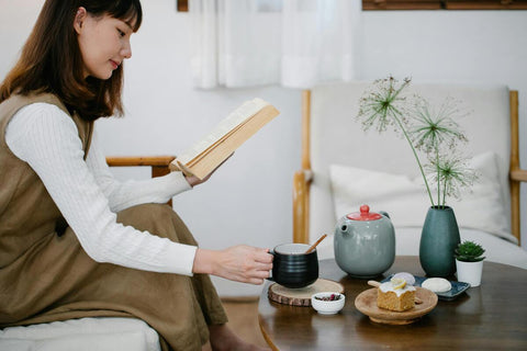 A woman reading while holding a cup of kava tea