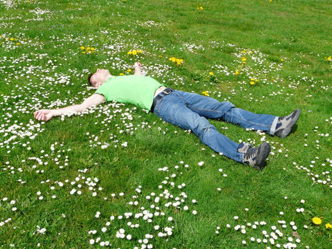 A man lying on the grass full of flowers